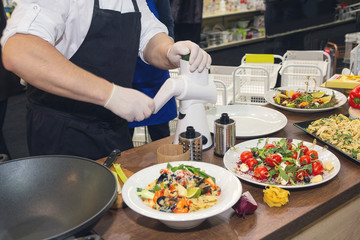 Cook in the kitchen cuts vegetables for salad