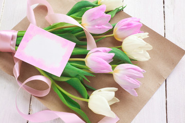International Women's Day. A bouquet of white and pink tulips with a ribbon on a white background. Greeting card. Spring. Selective focus.