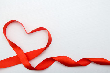 Heart shape made of red ribbon on white wooden Background. copy space - Valentines and 8 March Mother Women's Day concept.