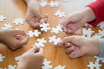 Hands of diverse people assembling jigsaw puzzle, team put pieces together searching for right...