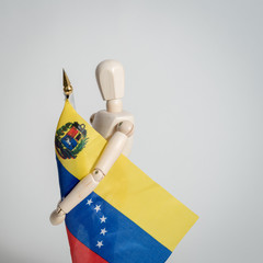 Venezuelan flag held by man made in wood on white background ideal for political and social conflicts in Venezuela and South America