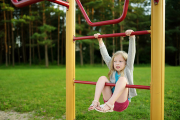 Cute little girl having fun on a playground outdoors in summer.