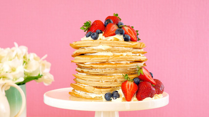 Shrove Pancake Tuesday, last day before Lent, stack of pancakes cake prepared with layers of whipped cream and fresh berries.