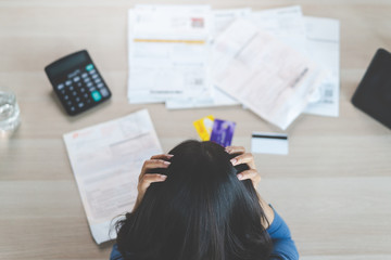 Top view of stressed young asian woman trying to find money to pay credit card debt. Selective focus on hand.