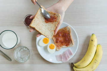 Person having breakfast on the table eat apple, egg, jam and milk the menu for dieting. plan.