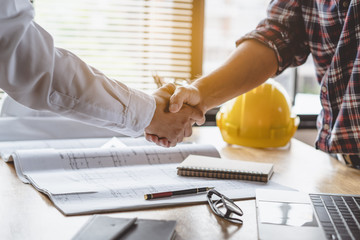 Client shaking hands with contractor after confirm blueprint to renovate house.