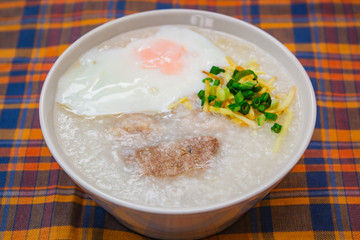 Rice porridge with soft boiled egg, ginger and chopped spring onion.