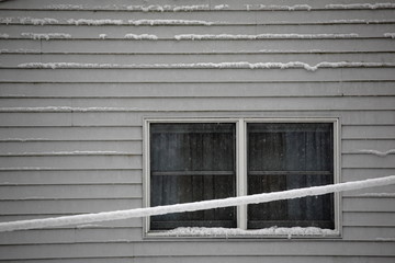 Fototapeta premium Snow on a House - Winter snow accumulates on the side of a suburban house. 