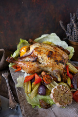 Homemade baked chicken with vegetable salad and herbs on vintage cutting board