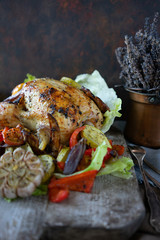 Homemade baked chicken with vegetable salad and herbs on vintage cutting board