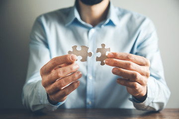man hand holding  two puzzle