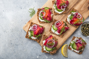 healthy sandwiches with wholegrain rye crisp bread, cream cheese, beet cured salmon and cucumber on...