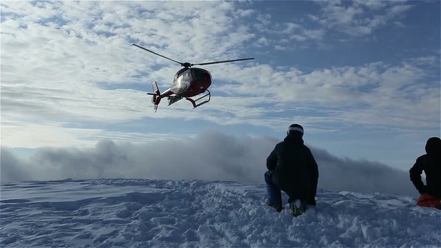 The helicopter left skiers on the slope of the mountain and flew raising a cloud of snow