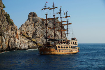 Tourists enjoying sea trip on board of a sailboat in front of impressive cliffs in Mediterranean...
