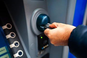man pushing credit card at cash dispenser