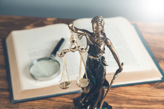 lady justice with book and magnifier on table