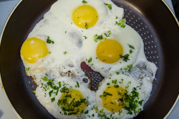 fried eggs in a pan sprinkled with greens