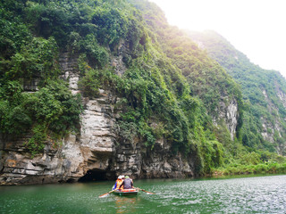 Fototapeta na wymiar The boat that was paddling along the waterway with high mountains in Halongbok, Vietnam