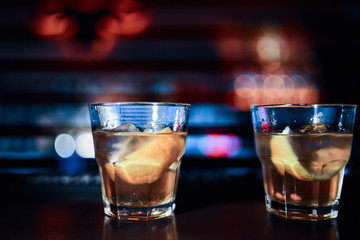 Two glasses of whiskey on the bar counter. Blurred background
