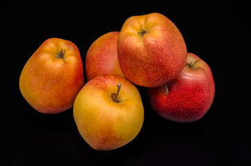 A group of five beautiful yellow with red spots of ripe apples on a black background
