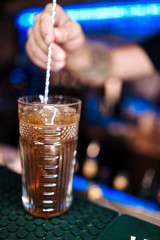 Fototapeta na wymiar Blurred barman hand on background creates soft alcoholic coctail at the bar at the night club
