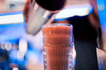Blurred barman on background creates soft alcoholic coctail at the bar at the night club
