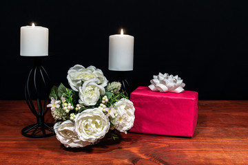 Beautiful bouquet of arranged flowers white candles on a holder with a present on a wooden table. mothers day, Easter, valentines, birthday, Christmas,