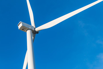 White wind turbine for alternative energy in day with blue sky background, electric clean power concept