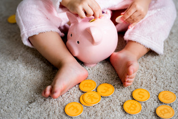 Little kid playing putting coins into piggybank