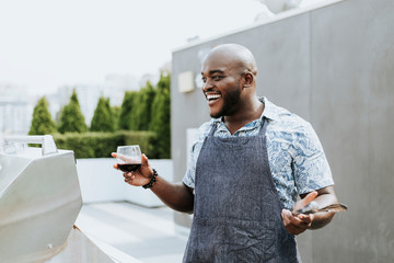 Cheerful chef with grilling tongs and a wine glass