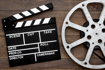 Filmings concept. Clapperboard and film stock on dark wooden background top view copy space