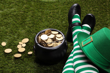 Girl with Leprechaun's striped socks standing on grass next to a black cauldron full of golden coins