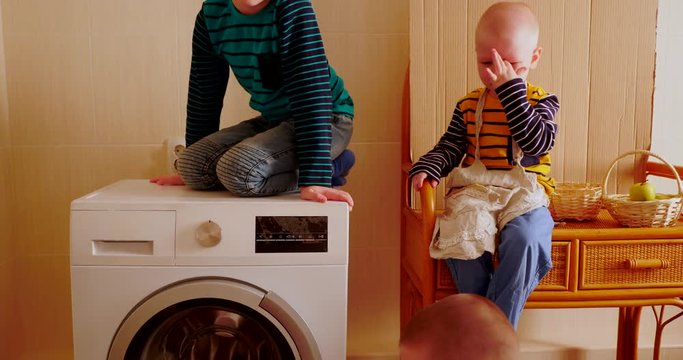 Parents bought new washing machine of new model latest generation. Children try to turn Washer on and wash some clothers. Three Happy boys are playing at home. Social assistance to large families.