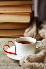 Love of books, reading. Stack of books on the wooden table.and origami paper craft the shape of a heart, cup of tea. Library, education, leisure time concept.