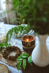 rustic festive table details with wild ferns, handmade decoration and candles. Country home dinner in summer evening.