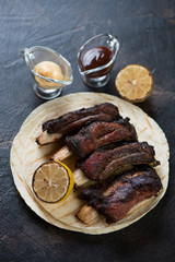 Barbecued beef ribs with dipping sauces on tortilla flatbread, studio shot