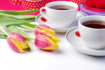 A table laid for Valentines Day. Two cups of tea and a bouquet of scarlet tulips