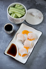 Chinese steamed har gao with shrimps on a grey concrete background, vertical shot, elevated view