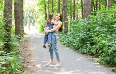 Family and nature concept - Young woman hold little daughter girl