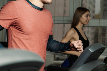 Fototapeta na wymiar Active beautiful fitness model girl and athletic man train on the treadmill in the gym.
