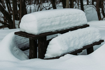 Detail of height snow cover on touristic wood table and bench