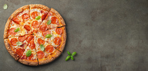 Tasty pepperoni pizza with basil on brown concrete background. Top view of hot pepperoni pizza....