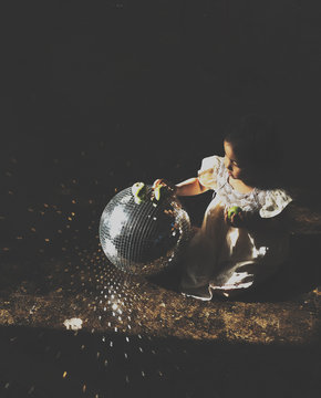 a girl playing with a disco ball