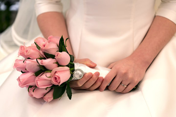 Bride holds a wedding bouquet. Very nice young woman in a white wedding dress holding a beautiful blossoming flower bouquet of various kinds of fresh real flowers, in pink, red and pastel cream color