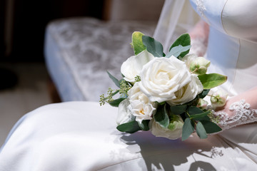 Bride holds a wedding bouquet. Very nice young woman in a white wedding dress holding a beautiful blossoming flower bouquet of various kinds of fresh real flowers, in pink, red and pastel cream color