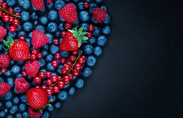 Berry mix on a black background with copy space. Strawberry, Raspberry, Red currant,  Blueberry and Blackberry, top view