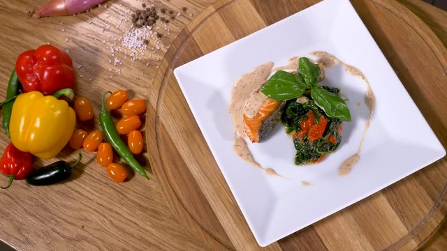 Meal salmon with spinach and vegetables on a wood table point of view.