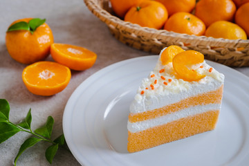 Orange cake on plate and fresh orange in basket