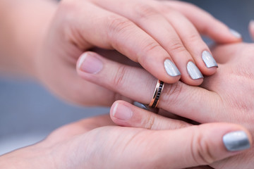 Obraz na płótnie Canvas Wedding theme, Bride putting ring on groom hand, and they holding hands with a nice manicure neat. Close up hands of man and woman put wedding ring on hand.