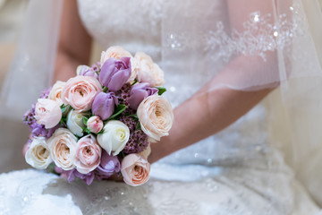  Bride holds a wedding bouquet. Very nice young woman in a white wedding dress holding a beautiful blossoming flower bouquet of various kinds of fresh real flowers, in pink, red and pastel cream color